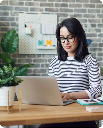 A woman in glasses works on her laptop, focusing on CE and UKCA certification processes for product compliance.